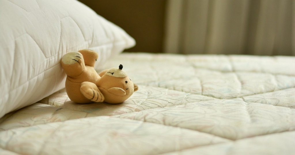 ベッドの上に置いてあるクマのぬいぐるみ